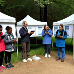 **

A diverse group of people outdoors, enthusiastically participating in a citizen science project. They are using tablets and smartphones to record data, with scientists nearby providing guidance and encouragement. The scene is bright and engaging, highlighting the collaborative aspect of data collection and the value of citizen contributions. Include visual aids like charts displayed on a nearby board or a pop-up tent acting as a central data collection point. Emphasize community involvement, showing various demographics actively engaged.

**